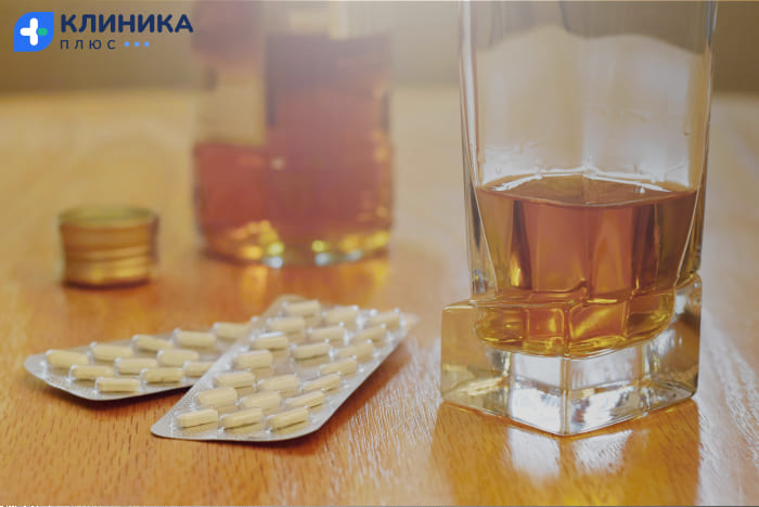 Таблетки, бокал и бутылка коньяка на столе
